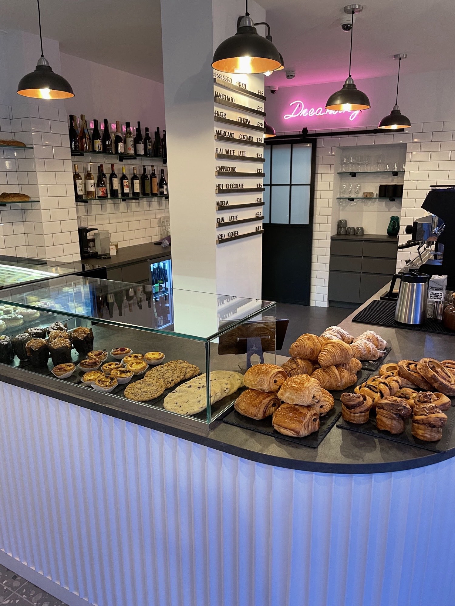 The pastry counter at Rise & Bloom, Hackney Road, with croissants, pain au chocolat and cinnamon rolls laid out beneath the espresso menu board